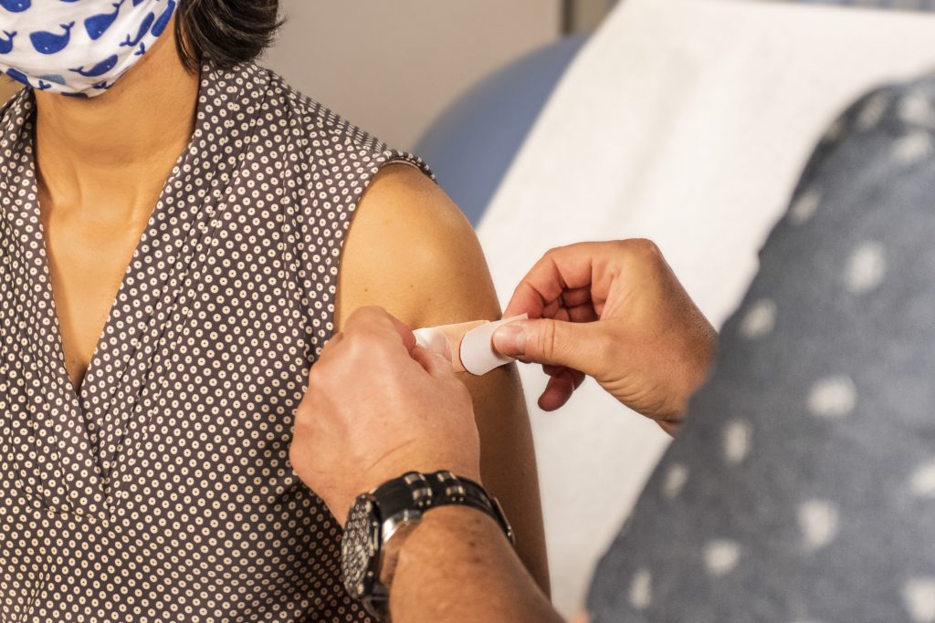 In this 2020 photograph, captured inside a clinical setting, a bandage has been placed on the injection site of a patient, who just received an influenza vaccine.
